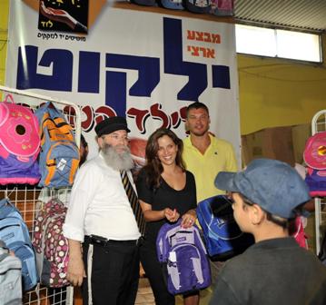 בתמונה: הרב גלויברמן עם  נעה תישבי ושאראס מחלקים תיקים לילדים  נזקקים.